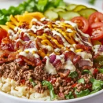 Delicious burger bowl with ground beef, fresh veggies, and special sauce, served in a white bowl on a wooden countertop.