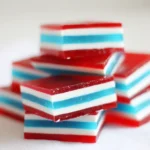 Close-up of red white and blue layered jello cubes on a white background